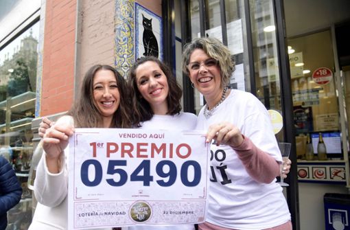 Drei Losverkäuferinnen in Sevilla halten die Nummer des Hauptgewinns hoch. Foto: AFP/Cristina Quicler