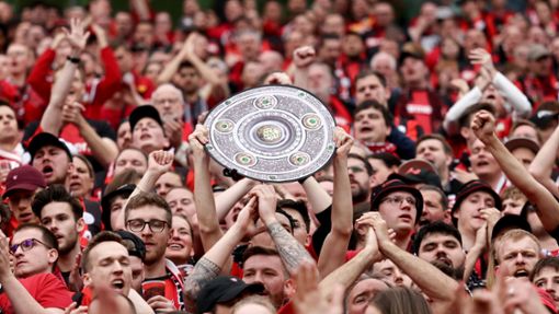 Fußball: Ein Leverkusener Fan hält während des Spiels eine Nachbildung der Meisterschale in den Händen. Bayer Leverkusen gewinnt die Deutsche Meisterschaft. Foto: Rolf Vennenbernd/dpa