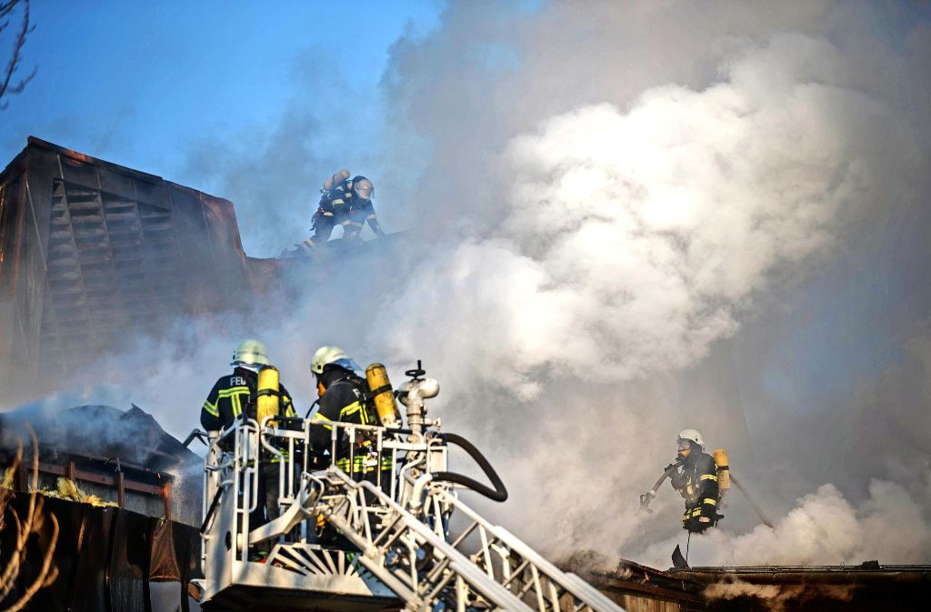 Feuerwehrleute bekämpfen Brandnester, die unter dem Dach des Bürgerzentrums bis zum Nachmittag schwelten.