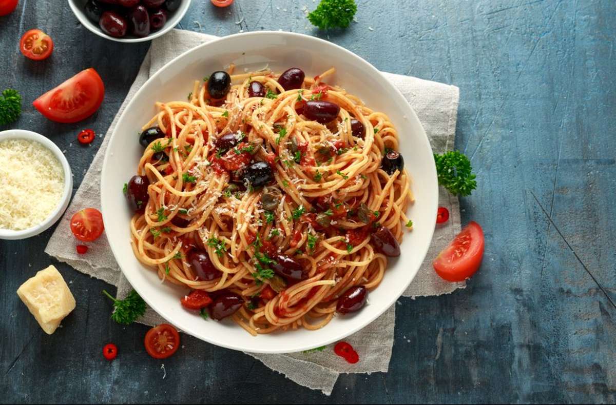 Leckere Spaghetti alla puttanesca mit Sardellen, Tomaten, Oliven und Kapern.