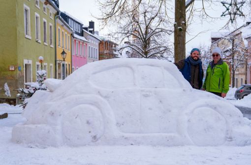 Eberhard Burger (rechts) und sein Nachbar Stefan Parnt stehen neben ihrem aus Schnee erbauten „Käfer“. Foto: dpa/Nicolas Armer