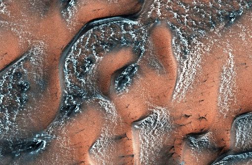 Frühling auf dem Mars:  Im Winter bedecken Schnee und Eis aus Kohlenstoffdioxid, sogenanntes Trockeneis,   die Dünen des Roten Planeten, erklärt die Nasa. Wenn die Sonne im Frühling  auf die Oberfläche  scheint, bricht die Eisschicht. Ausströmendes Gas wirbelt dunklen Sand auf, zudem bleibt Eis übrig. All dies  sorgt oft für „wunderschöne Muster“, so die Nasa. Foto: NASA