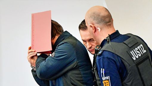 Mit einem Ordner vor dem Gesicht wird der Angeklagte in Saal 153 geführt. Foto: dpa/Bernd Weißbrod