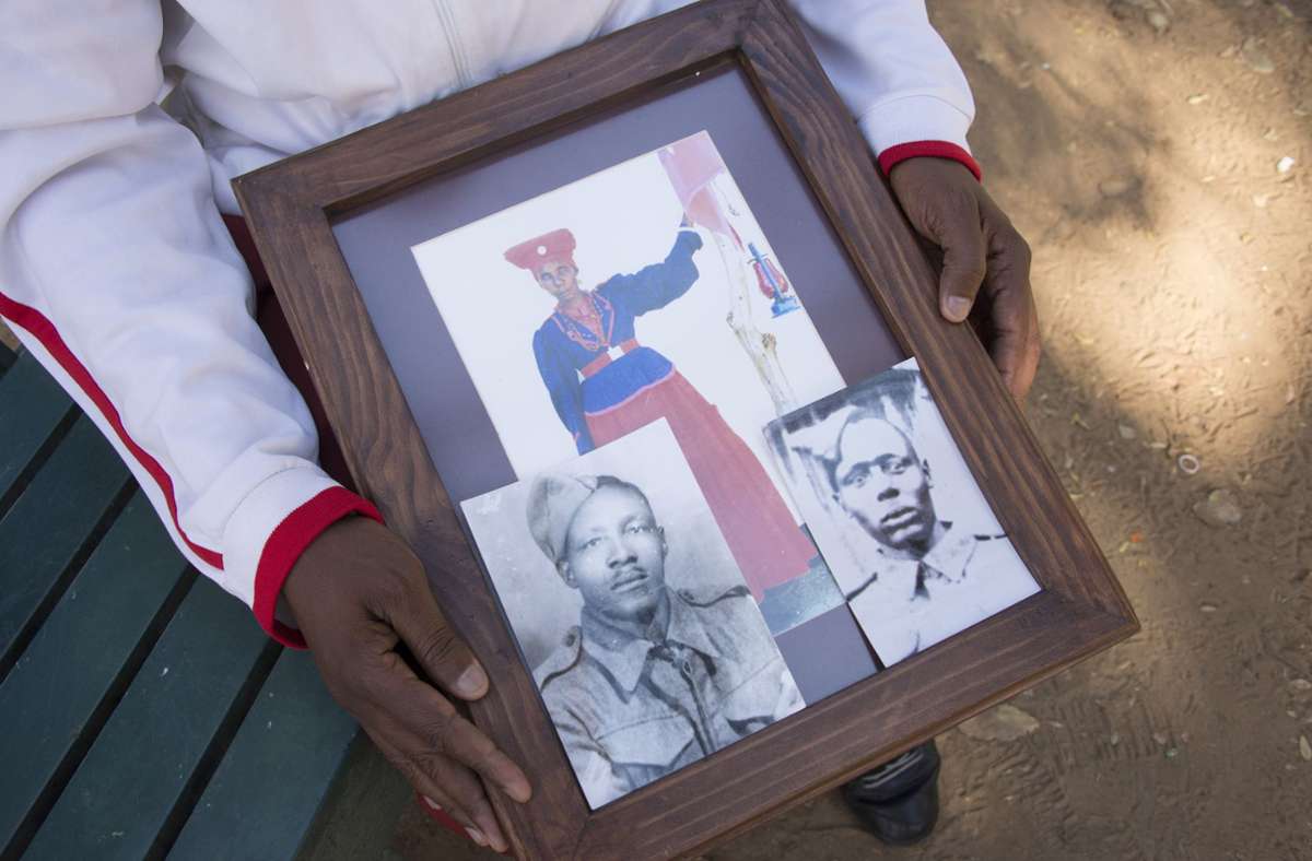 Uruanaani Scara Matundu, ein Vertreter der Herero-Gemeinde, zeigt in einem Park in Windhuk Fotos seiner Vorfahren. Foto: dpa/Gioia Forster