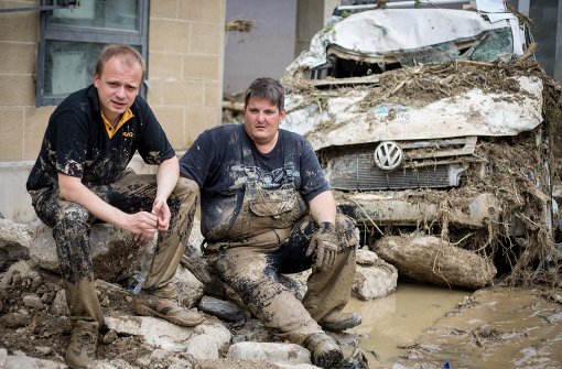 Die Gesichter zweier Helfer: Manuel Taffner (links) und Dimi Karagiannis machen neben einem völlig zerstörten Auto eine Pause. Foto: dpa