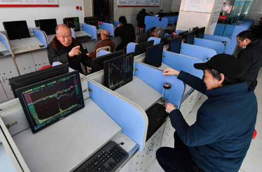 Zwei Investoren  diskutieren über den Finanzmarkt Börsenverlauf, während Monitore den Shanghai Composite Index anzeigen. Foto: dpa/Sheldon Cooper