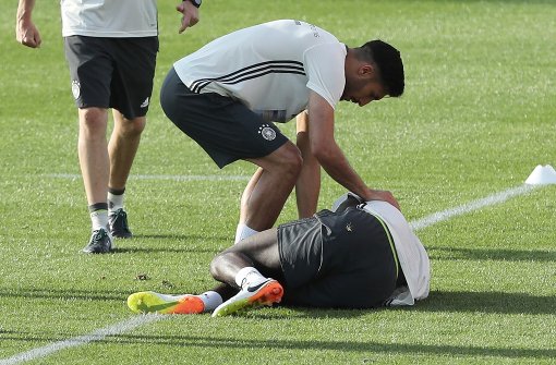 Emre Can beugt sich über den verletzten Antonio Rüdiger während des öffentlichen Trainings der deutschen Fußballnationalmannschaft. Foto: dpa