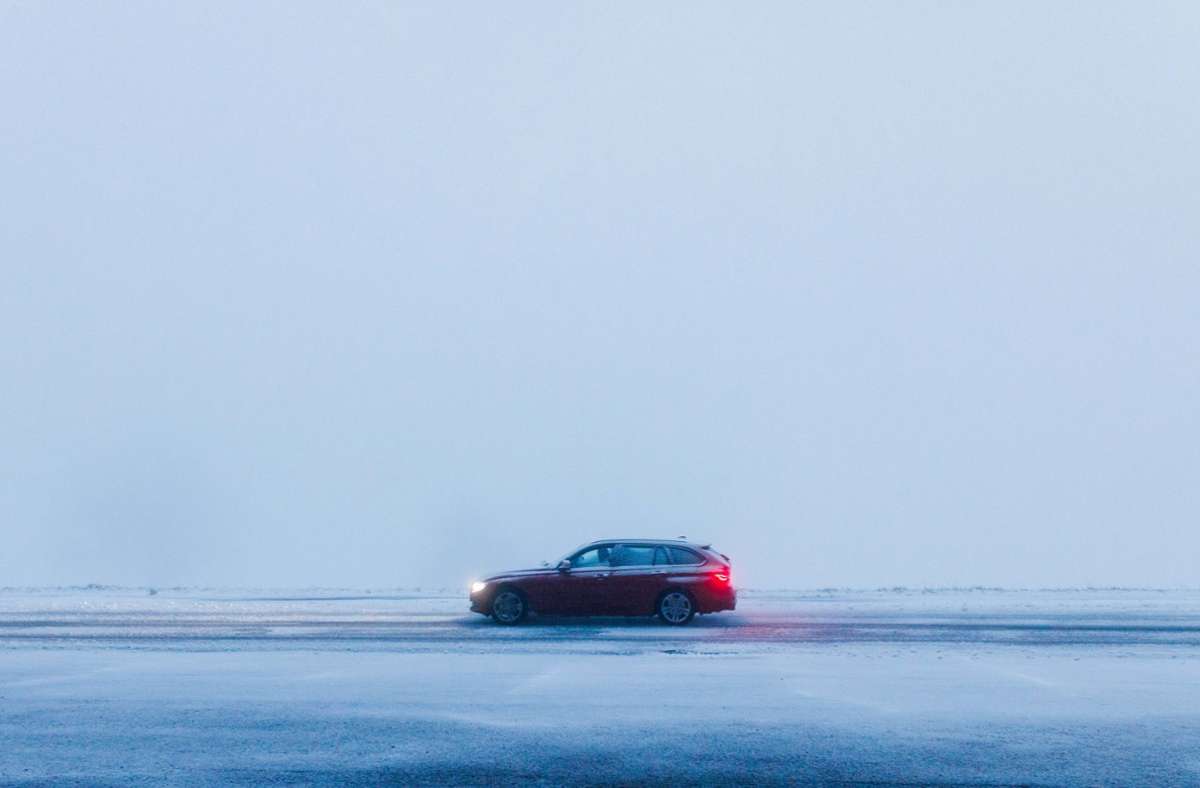 Ein Auto fährt dort durch den frisch gefallenen Schnee.