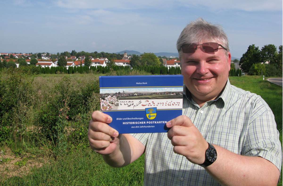 Markus Munk mit seinem neuen Postkartenbuch vor der Silhouette Schmidens