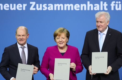 Bundeskanzlerin Angela Merkel (CDU), der CSU-Vorsitzende Horst Seehofer und der kommissarische SPD-Vorsitzende Olaf Scholz zeigen den unterzeichneten den Koalitionsvertrag. Foto: dpa