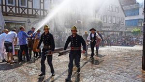 Die historischen Feuerwehrleute löschen nicht nur den vorgetäuschten Rathausbrand, sondern sorgen auch für die Erfrischung der Zuschauer. Foto: Edgar Layher