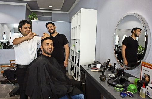 Der Syrer Nidal Mohammad (links) schneidet im Salon von Berat Kabak mit viel Schwung Haare. Für die Fotografin hat sich Osamah Abdul Qader  Ahmed auf den Friseurstuhl gesetzt. Der Iraker hat bei einem Filderstädter Bäcker Arbeit gefunden Foto: Natalie Kanter
