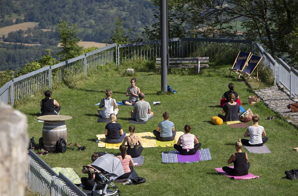 Konzentration bitte: Beim Yoga auf dem Hohenneuffen haben die Teilnehmer einen tollen Ausblick – und dank der vielen Besucher auch Zuschauer. Foto: Michael Steinert