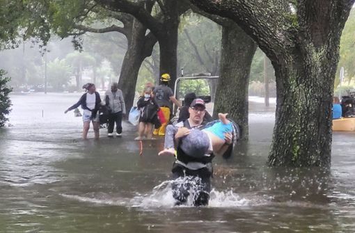 Orange County, Florida: Ein Feuerwehrmann trägt eine Person über eine überflutete Straße. Foto: dpa