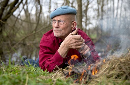 Der deutsche Survival-Experte und Aktivist für Menschenrechte, Rüdiger Nehberg, liegt in einem Wald auf seinem Privatgrundstück neben einem selbst entfachten Lagerfeuer. Foto: dpa/Axel Heimken
