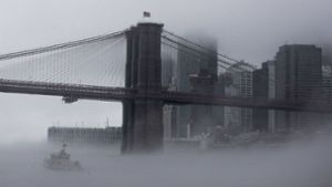 Ein Boot der New Yorker Polizei fährt  unter der Brooklyn Bridge durch  dichten Nebel. Foto: dpa