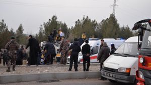 Rettungskräfte stehen auf und vor einem, durch den Bombenanschlag, stark beschädigten gepanzerten Polizeifahrzeug am 16.01.2017 im Bezirk Sur, der südöstlichen Provinz Diyarbakr (Türkei). Foto: AFP