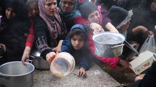 Palästinenser stehen während der israelischen Luft- und Bodenoffensive für die kostenlose Verteilung von Lebensmitteln an. Foto: Hatem Ali/AP/dpa