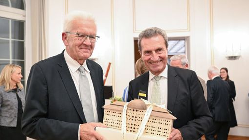 Winfried Kretschmann (l.)  überreichte Günther Oettinger bei einem Empfang ein Bienenhotel in Form der Villa Reitzenstein. Foto: dpa/Bernd Weißbrod
